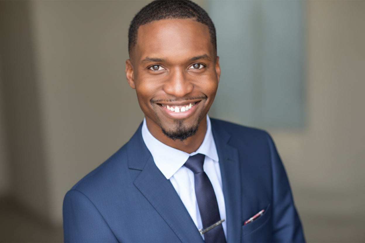 Man wearing a blue suit with a white shirt and dark tie against a neutral background